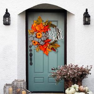 Close-up of fall wreath with maple leaves, berries, and hello fall sign on blue door