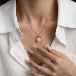 Collier avec pendentif crabe doré et zircons brillants sur une chemise en lin blanc