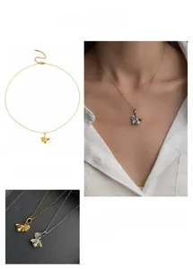 Dettaglio della collana con ciondolo ape e cuore con perle su catena dorata