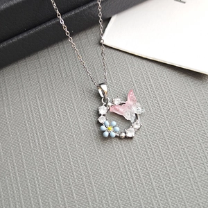 Collier en argent avec pendentif papillon en émail rose et fleur bleue en couronne