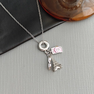 Collier en titane argenté avec pendentifs appareil photo et Tour Eiffel sur fond gris