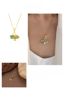 Détails du collier doré avec pendentifs avion, globe et valise sertis de zircons