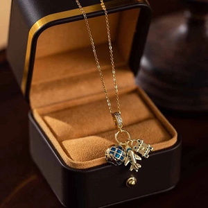 Vue détaillée de pendentifs avion et globe avec zircons sur un collier doré