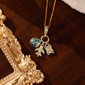 Détail du collier de voyage avec avion doré, globe bleu et breloque de valise