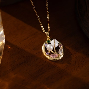 Macro detail of oval pendant with pink zircon floral design on gold chain necklace