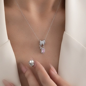 Macro view of a square sugar pink zircon pendant necklace with pavé stones on a model