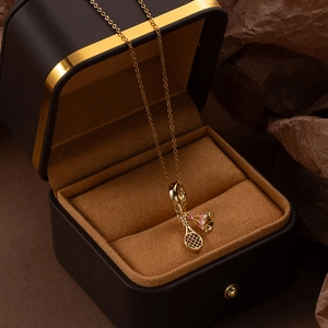 Detailed view of golden badminton racket and pink enamel shuttlecock pendant necklace