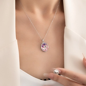 Detail of French vintage purple flower pendant with baroque pearl on silver chain