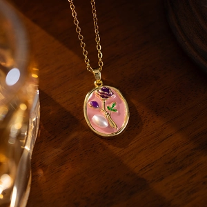 Detail of vintage French floral pendant with purple rose and baroque pearl on gold chain