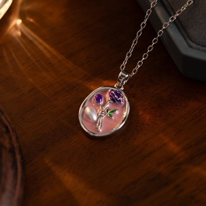 Detail of vintage silver necklace with pink enamel purple rose and baroque pearl