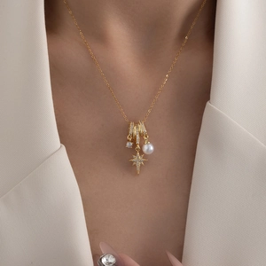 Elegant gold titanium necklace with starburst pendant and white pearl on model