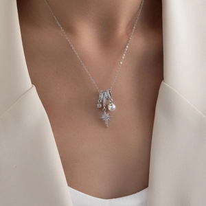Detail of silver necklace with starburst pendant, white pearl and zircon on model