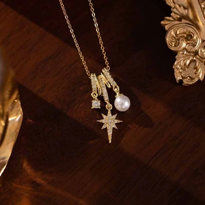 Detail of gold necklace with pearl, zircon, and diamond-set star pendant on wood background
