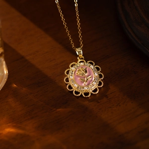 Close-up of vintage rose pendant necklace with pink enamel and pearl detailing