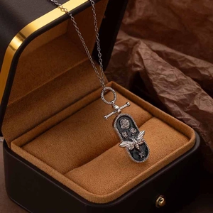 Close-up of vintage silver bee and rose relief on an oval titanium steel pendant