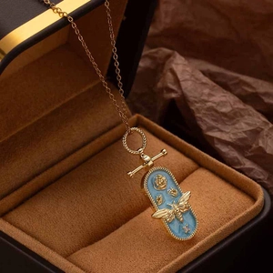Detailed close-up of a vintage golden bee necklace with light blue enamel and rose motif