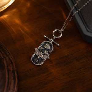 Detailed close-up of retro silver necklace with 3D bee and rose relief on dark wood