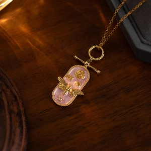 Detailed close-up of a 3D bee and rose relief on a pink enamel vintage pendant necklace