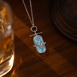 Detailed macro of a vintage silver bee and rose pendant on light blue enamel plate