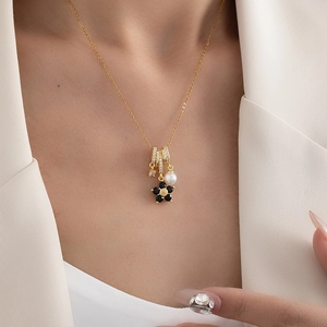 Detail of flower necklace with pearls and zircon charms on gold chain worn by model