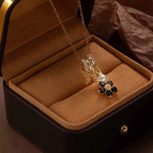Golden flower necklace with pearls and colorful zircons displayed on a velvet jewelry box