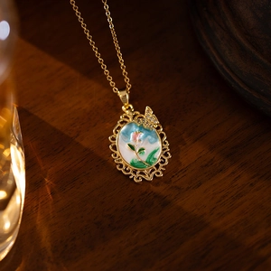 Détail de ce pendentif tulipe en émail rétro avec bordure en dentelle dorée et papillon