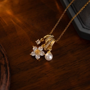 Close-up of golden necklace with zircon flower pendant and elegant white pearl drop