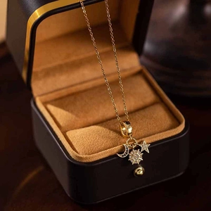 Macro detail of gold-plated sun, moon and star pendant necklace on jewelry gift box
