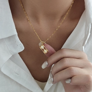 Elegante collana a clessidra dorata con pendente in opale indossata da una modella