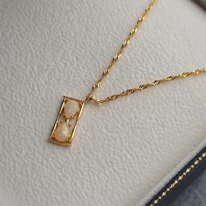Elegante collana a clessidra dorata con pietre di opale su una scatola bianca