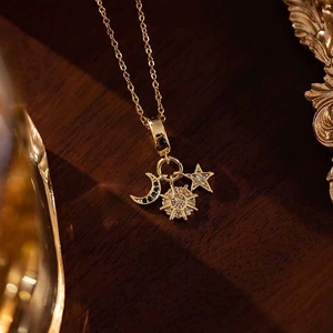 Close-up of gold sunflower necklace with moon and star pendants featuring blue zircons