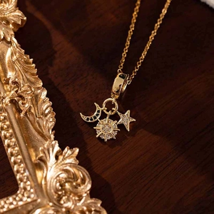Close-up of golden star moon and sunflower pendants on a delicate chain necklace