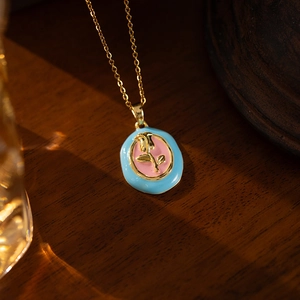 Detail of vintage tulip pendant featuring pink enamel and golden rose relief on chain