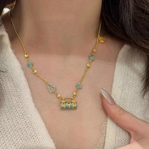 Exquis collier avec pendentif cadenas en émail bleu et finition dorée porté par un modèle