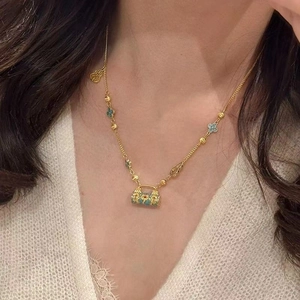Détail du collier doré avec pendentif cylindre en émail bleu et trèfles décoratifs
