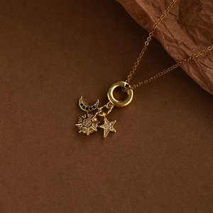 Golden necklace with sun, star and moon celestial charms on a fine chain link