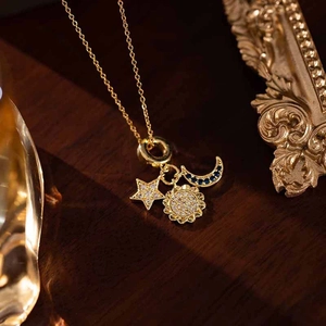 Detailed view of celestial sun, moon, and star charms on a gold chain necklace
