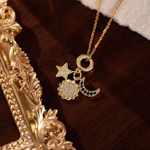 Detail of gold star moon and sun charms with blue and white zircon inlays on fine chain
