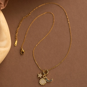 Golden sun star and moon necklace with sparkling zircons on a textured brown background