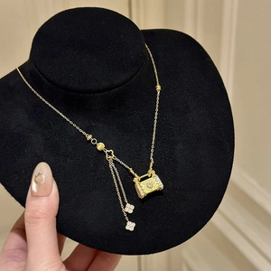 Détail du collier trèfle doré avec pendentif sac à main en cristal sur présentoir