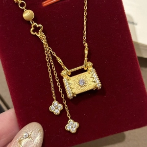 Collier pendentif cadenas doré avec glands de trèfle et cristaux sur velours rouge
