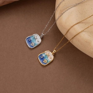 Blue enamel starfish seashell pendant necklace in gold and silver finishes on textured background