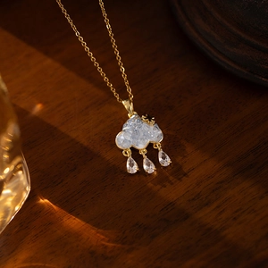Elegant gold cloud necklace with light blue stones and zircon raindrops on wood