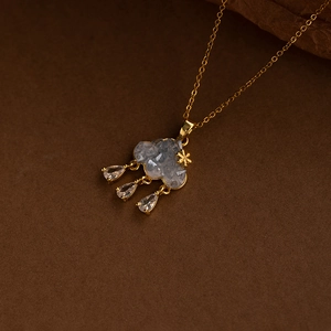 Blue cloud necklace with gold trim and zircon raindrops on a brown textured background