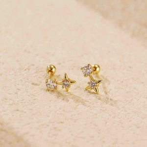 Goldene Stern-Ohrstecker mit Zirkonia-Steinen und Schraubverschluss auf Steinfläche