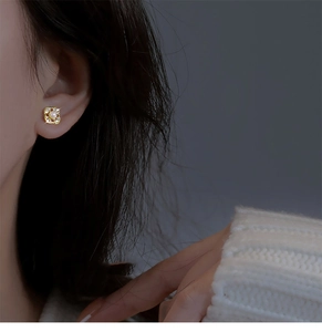 Detailed view of elegant gold flower earring with central pearl and pavé crystals on ear