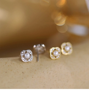 Macro detail of silver and gold clover earrings with white pearls and sparkling zircons