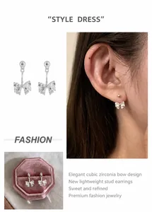 Detail view of silver bow earrings with transparent zircon inlay and polished beads
