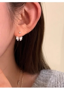 Close-up of bow knot earrings with white marquise zircon stones worn by a model
