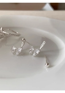 Detailed macro shot of bow-shaped silver earrings with sparkling zircon stones in a ceramic dish